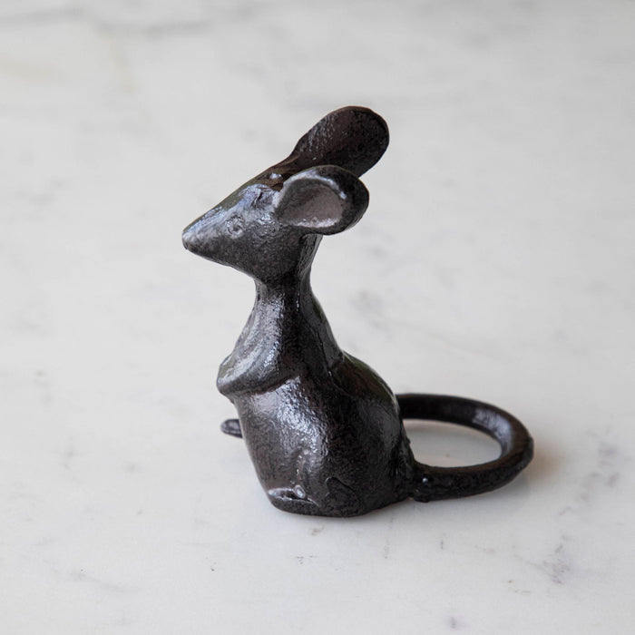 A cast iron mouse on a marble table.