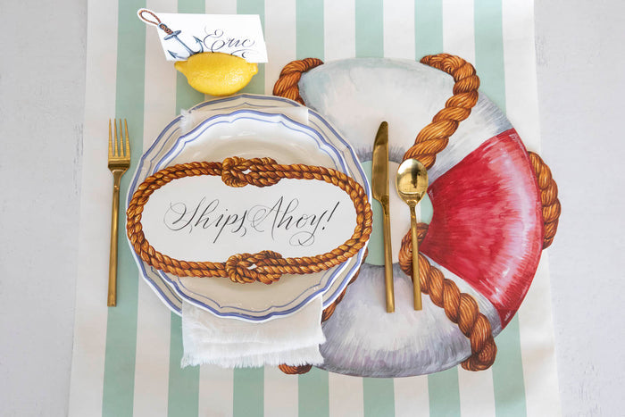 Top-down view of a nautical place setting featuring a Sailors' Knot Table Accent with "Ships Ahoy!" written on it in elegant script.