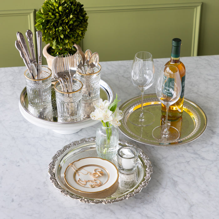 Dining table setting with silverware, glasses, and a bottle of wine on a marble surface.