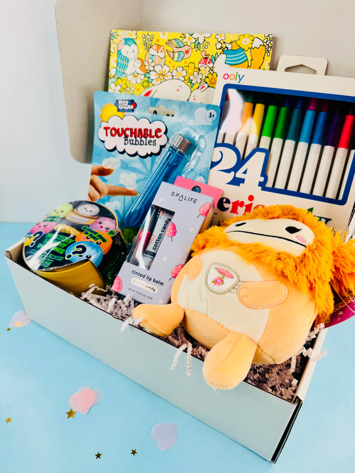 Gift box with plush toy, books, and stationery items on a light blue background