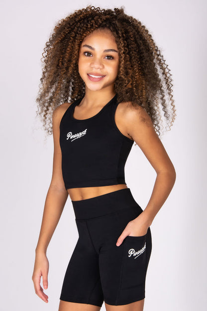 Girl wearing a black sports outfit with 'Pineapple' branding on a white background