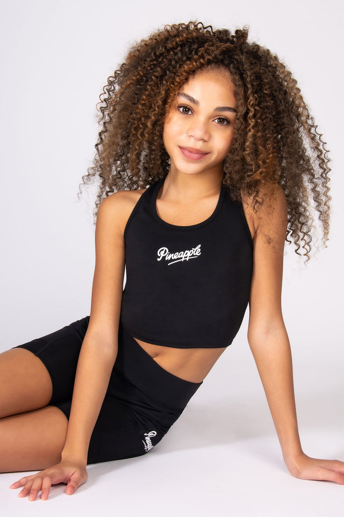 Girl wearing a black sports vest and matching shorts on a white background