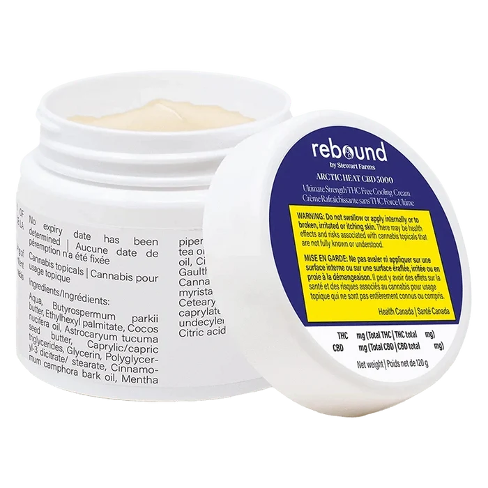Tilted view of an open jar showing pale cream and the label of Arctic Heat Cbd 5000 Cooling Cream with a blue and yellow warning panel.