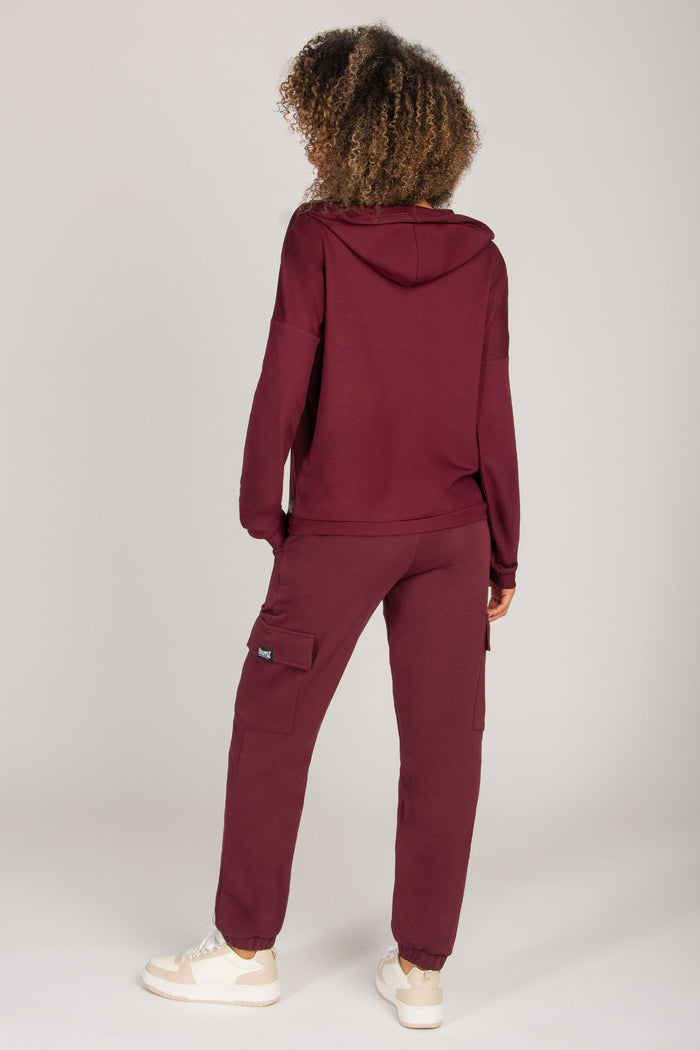 Woman wearing a burgundy tracksuit on a white background