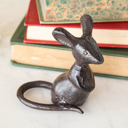 A cast iron mouse in front of a stack of books.