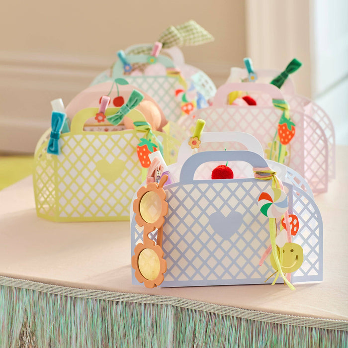 Colorful paper craft bags with decorative elements on a wooden surface.