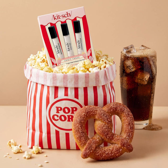 Popcorn bucket with popcorn, a glass of soda, and a pretzel on a beige background