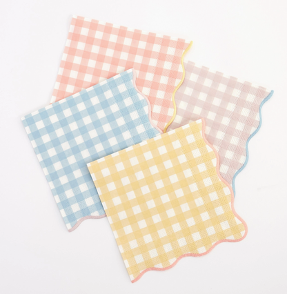 Four checkered napkins in pink, blue, yellow, and white on a light gray background