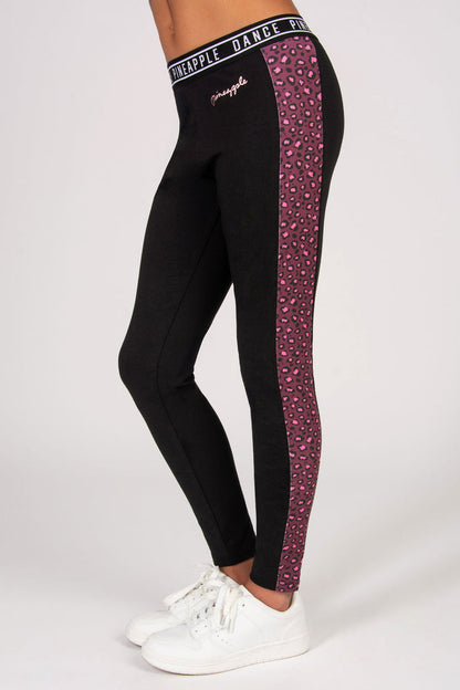 Black leggings with pink leopard print side panels and white sneakers on a light gray background