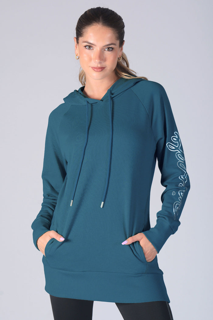 Kianna Louise wearing a teal hoodie with drawstrings and concealed pockets on a grey background