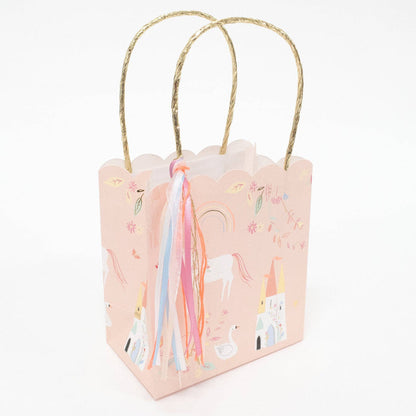 Small pink gift bag with unicorn design and gold handle on a white background