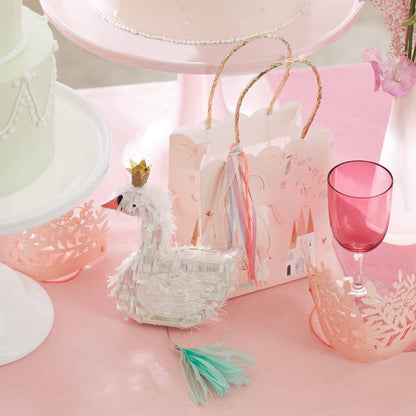 Decorative swan basket with a pink background featuring a cake and glass.