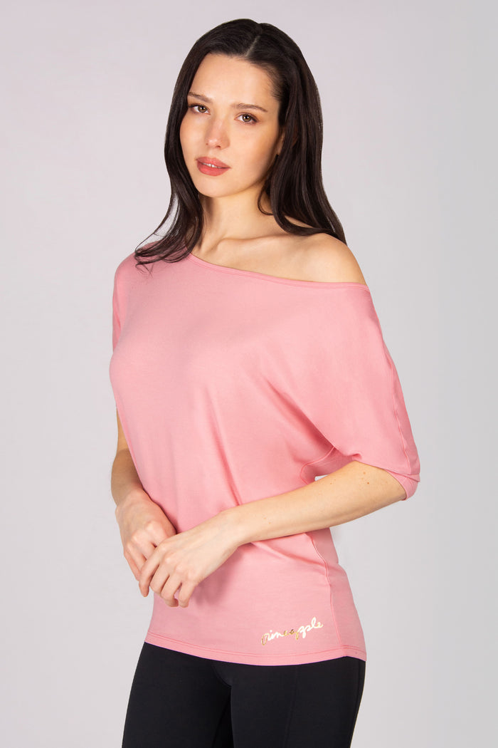 Woman wearing a pink off-shoulder top  on a plain background