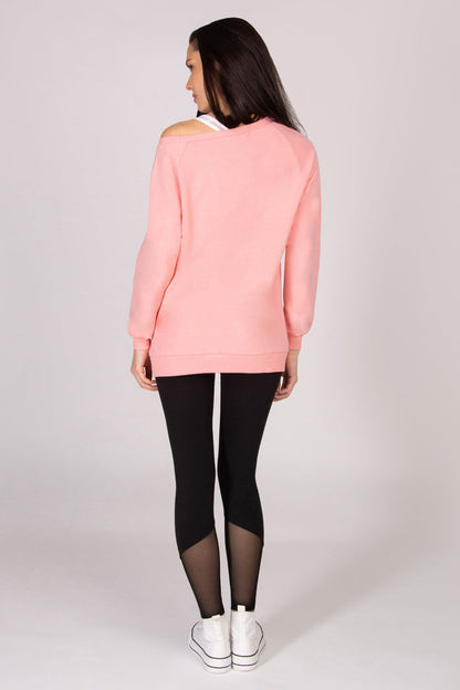 Woman wearing a coral pink sweater and black leggings on a white background