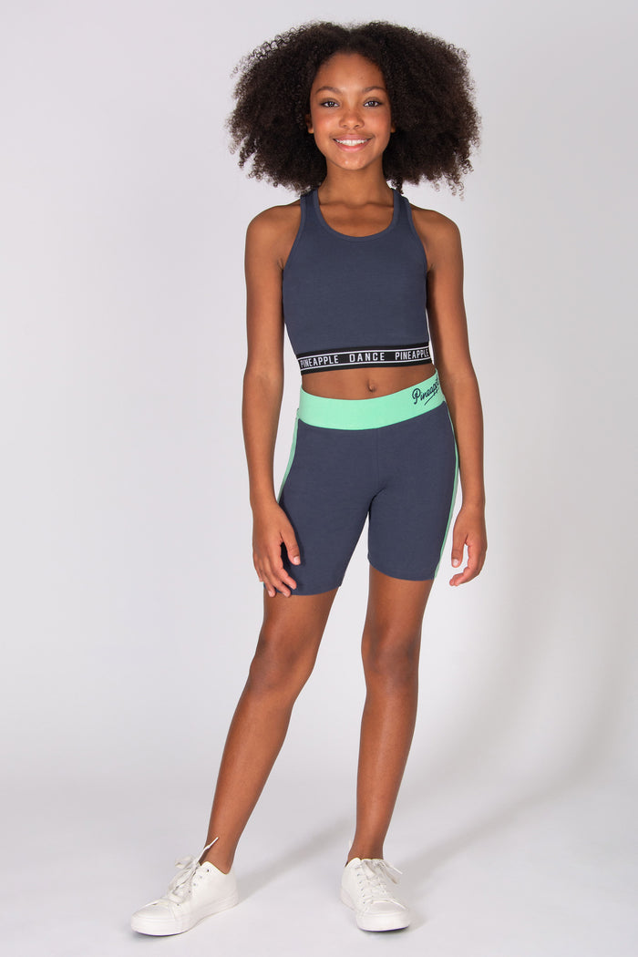 Girls wearing dark grey cycling shorts with mint green side panels and contrast waistband with matching sports top on a grey background