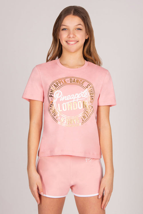 Teenager wearing a pink t-shirt and shorts set with dance print on a plain background