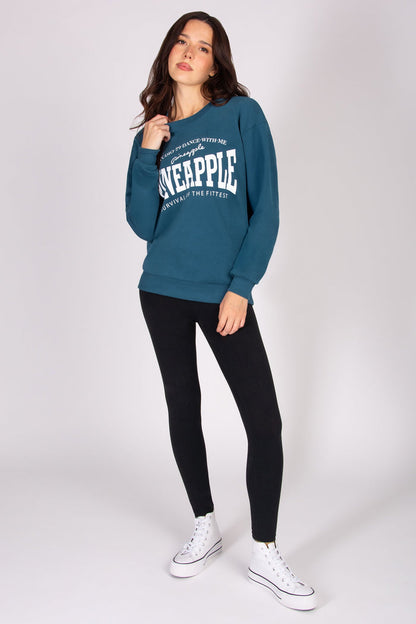 Woman wearing a teal sweatshirt with text, black leggings, and white sneakers on a white background