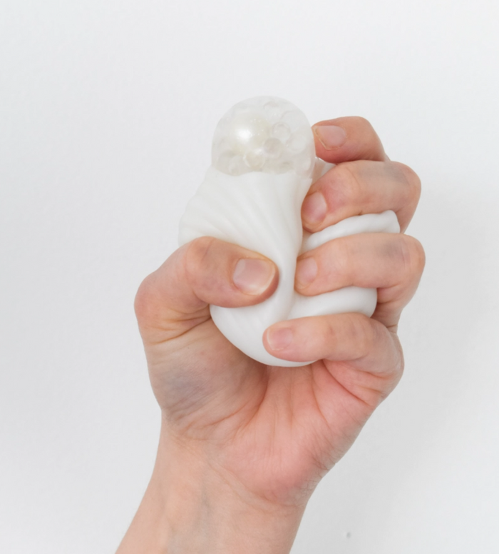 Hand holding a white stress ball against a light gray background