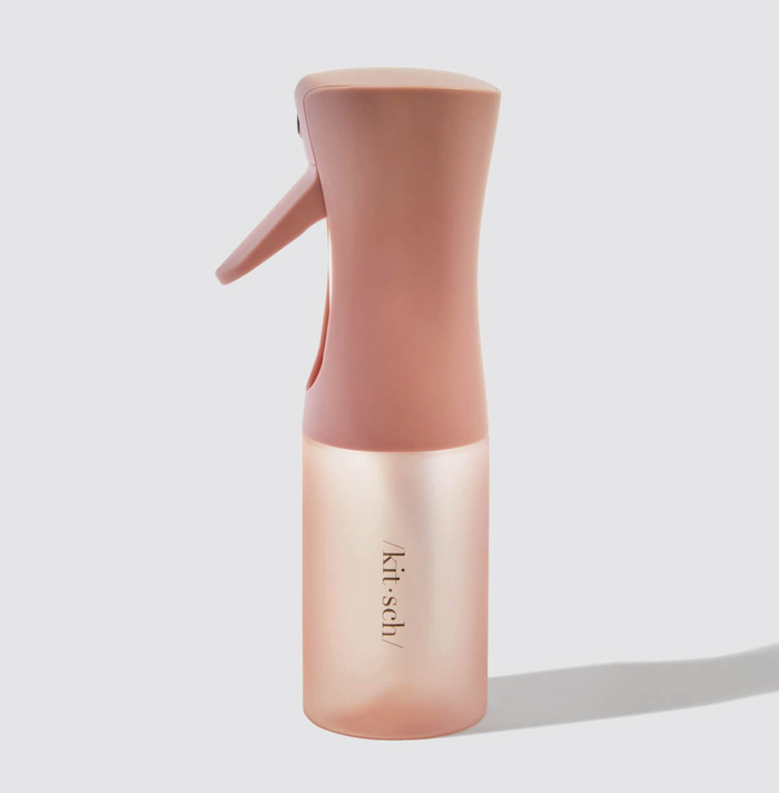 Pink spray bottle with 'kit-sch' branding on a light gray background