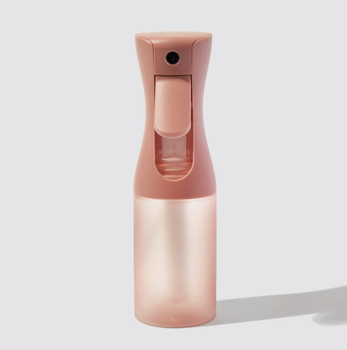 Pink spray bottle on a light gray background