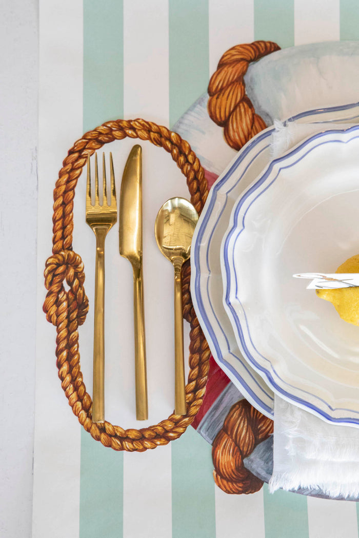 Close-up of a Sailor's Knot Table Accent under the cutlery of a nautical place setting.