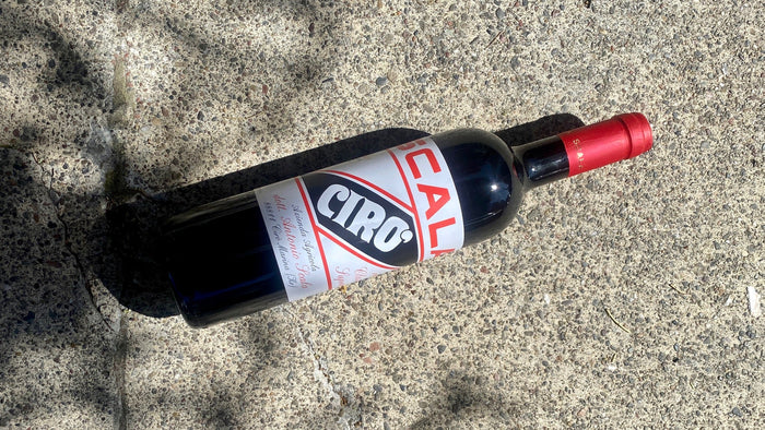 Wine bottle lying on its side with red foil cap and label visible