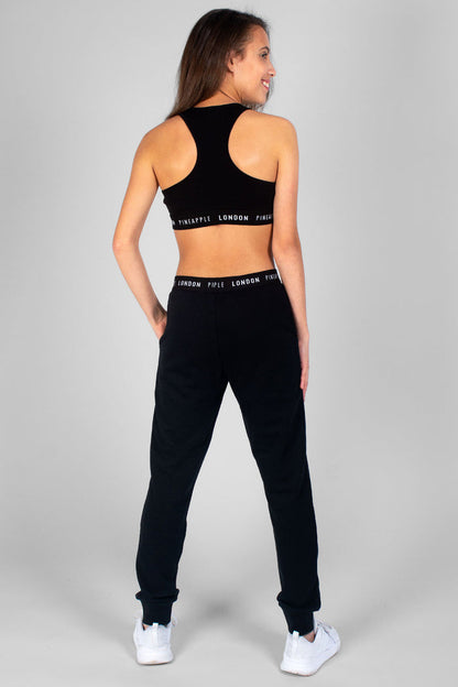 Girl wearing black Script Joggers and black Srip Crop Top with logo hem