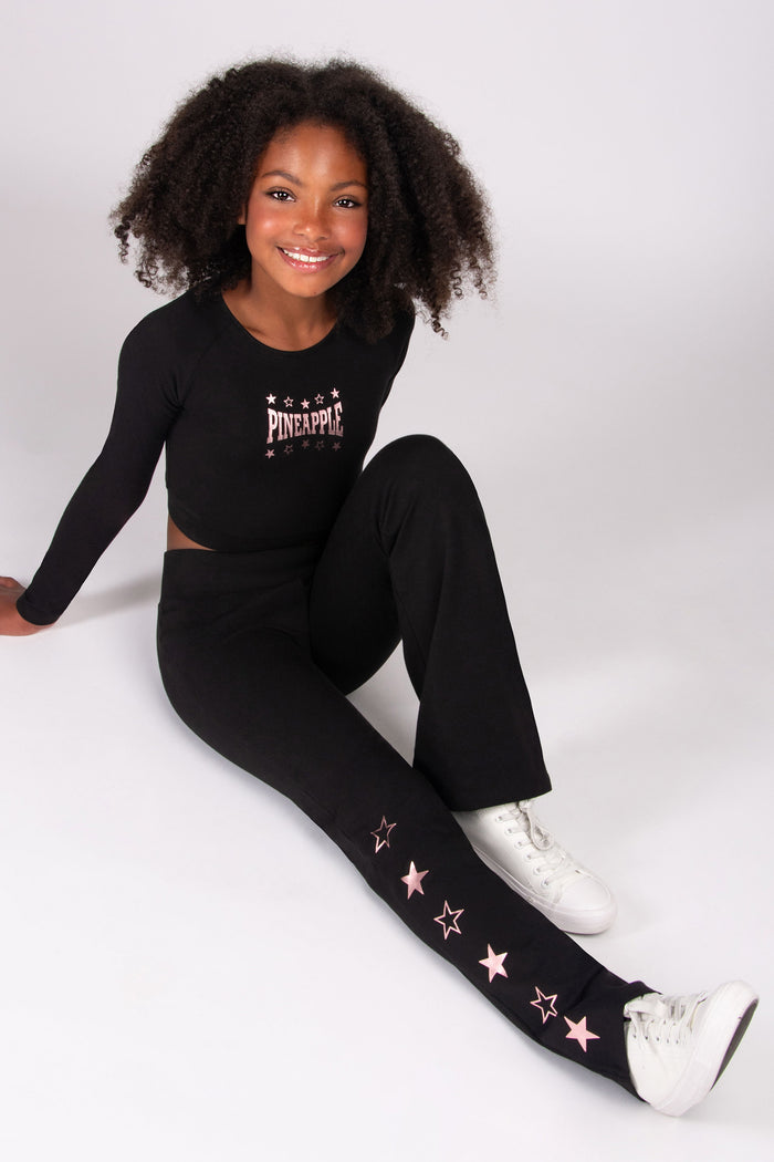 Child wearing a black dance outfit with star patterns on a white background