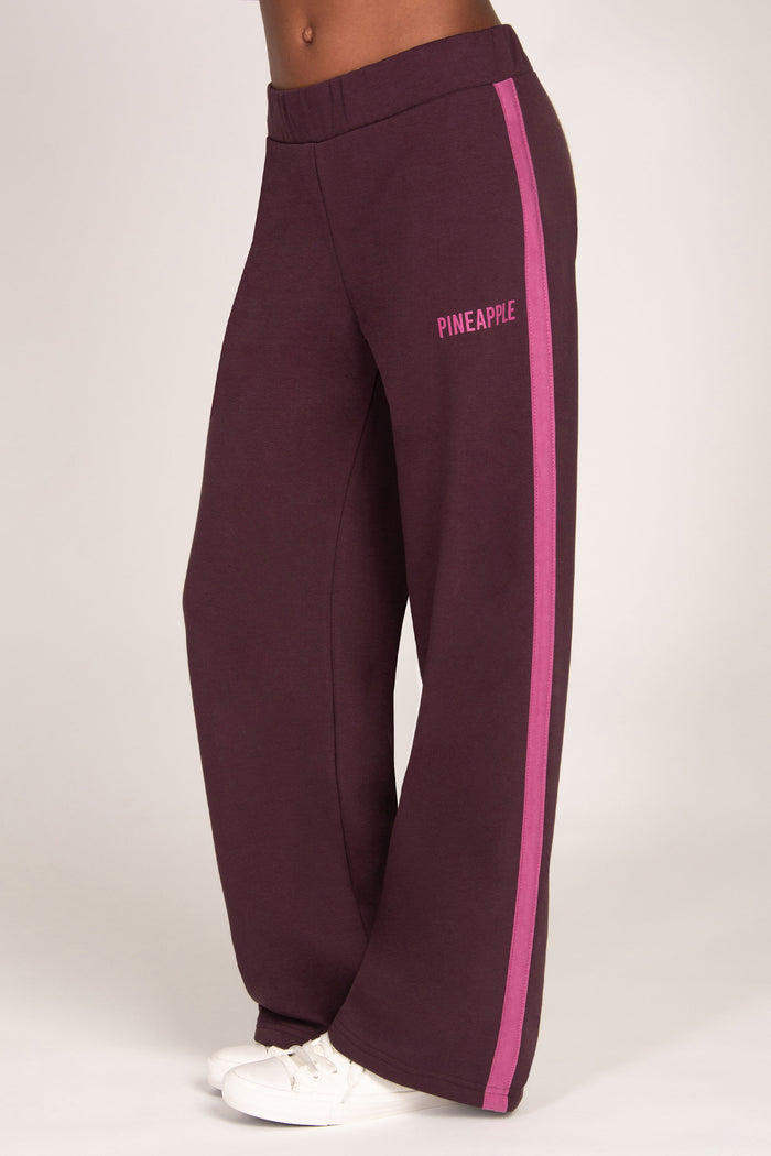 Maroon brown trousers with pink side panel and 'Pineapple' branding on a white background