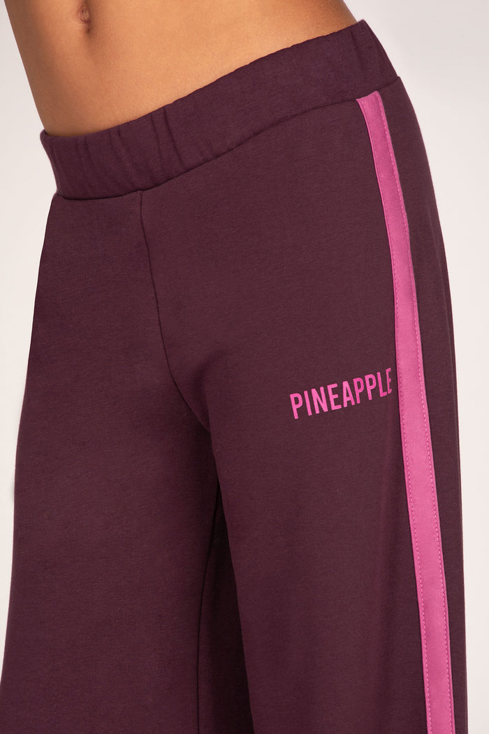 Maroon sweatpants with pink side stripe and 'PINEAPPLE' logo on a white background