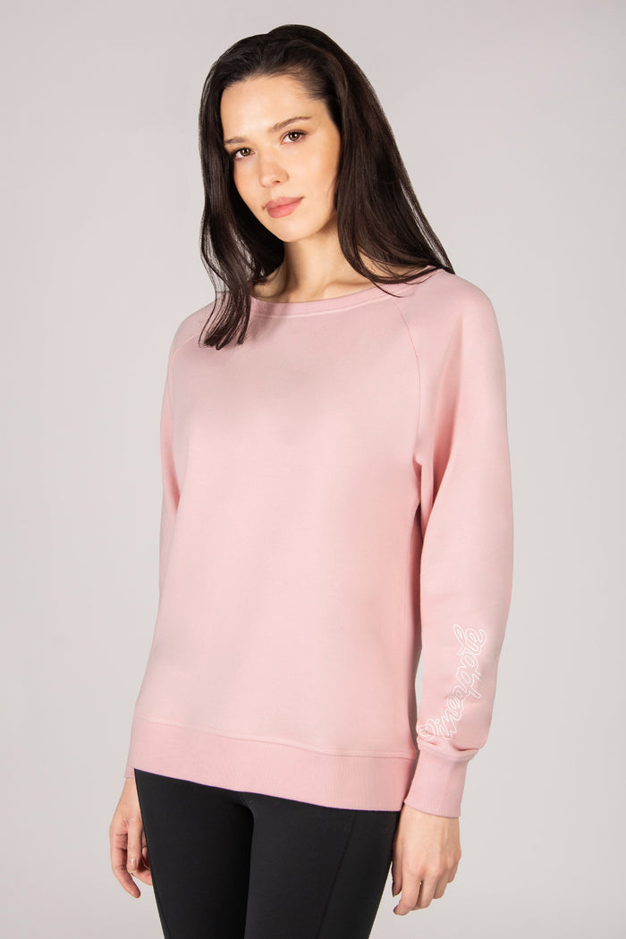 Woman wearing a light pink sweatshirt against a plain background
