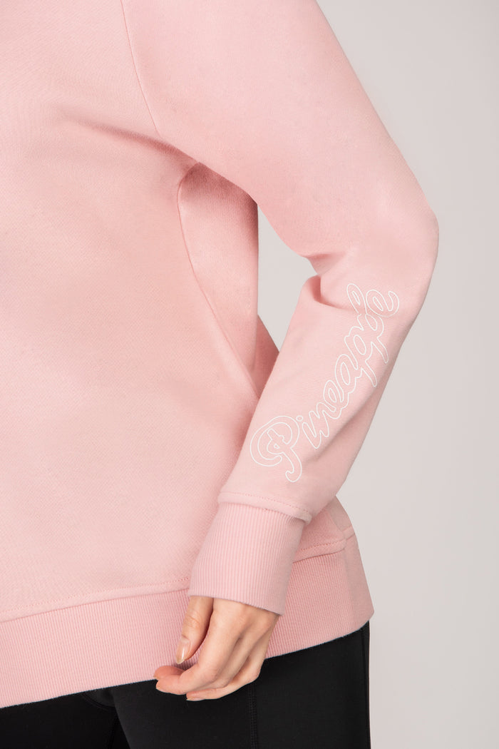 Detail shot of pink sweatshirt with 'Pineapple Dance' logo print on sleeve