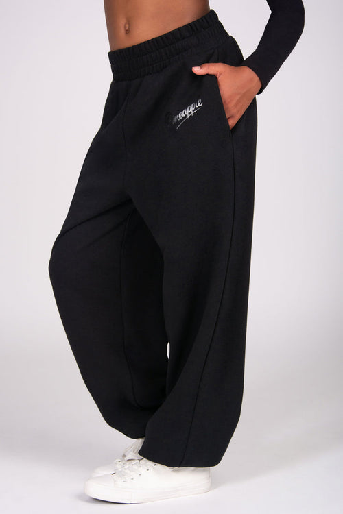 Black oversized sweatpants with side pockets worn by a person on a white background