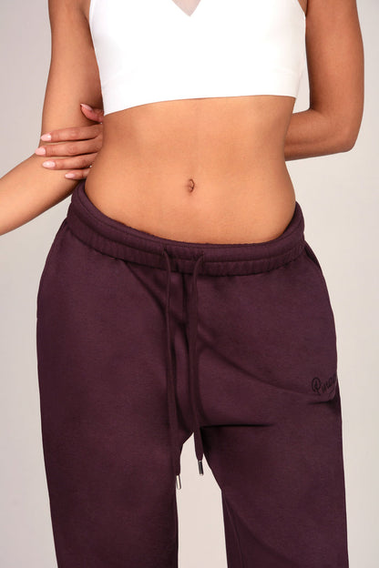 Close up shot of fold-down elasticated waistband of dark aubergine joggers.