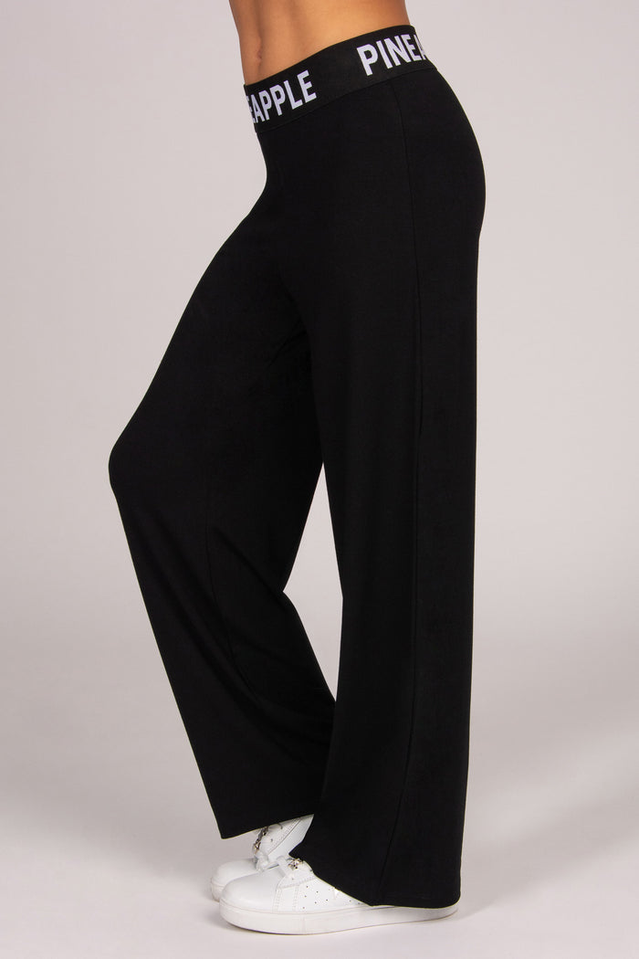 Black wide-leg viscose trousers with an elasticated waistband on a plain background