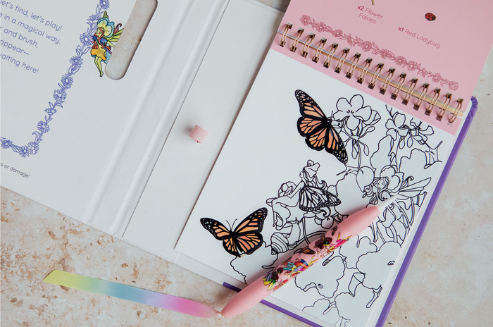 Coloring book with butterfly designs and a pink crayon on a light surface