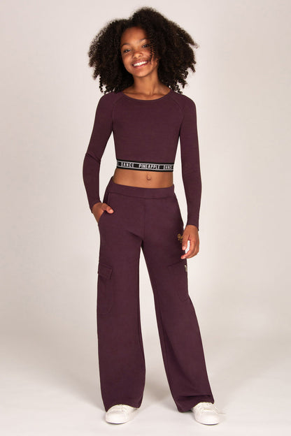 Girl wearing a maroon brown wide-leg trousers with matching long-sleeve top on a white background