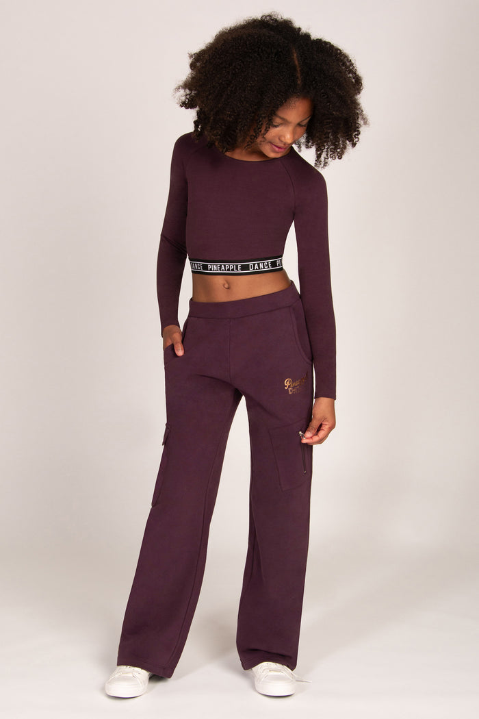 Girl wearing a maroon brown wide-leg trousers with matching long-sleeve top on a white background