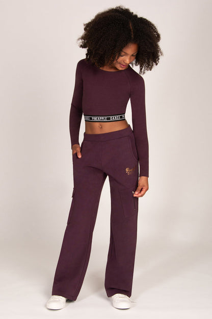 Girl wearing a maroon brown wide-leg trousers with matching long-sleeve top on a white background