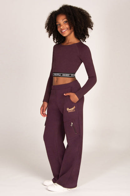 Girl wearing a maroon brown wide-leg trousers with pockets and matching long-sleeve top on a white background