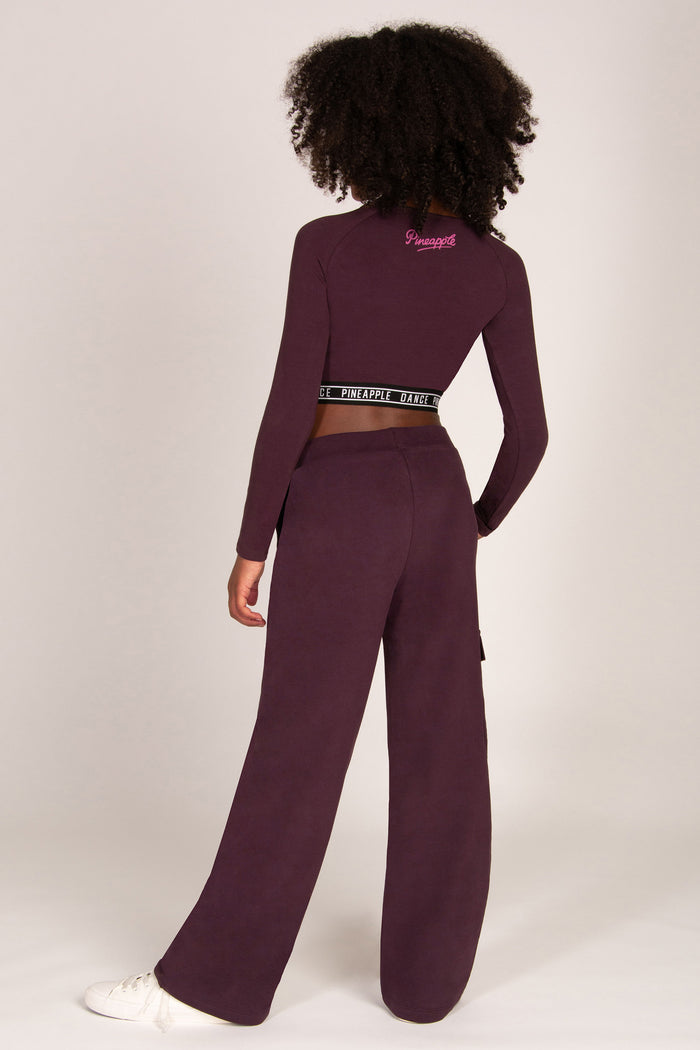 Girl wearing a maroon brown wide-leg trousers with pockets and matching long-sleeve top on a white background